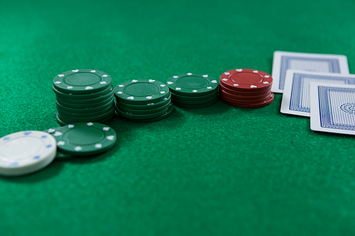 Close-up of poker chips and cards on green table