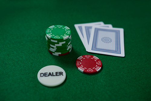 High angle view of dealer coin and chips with cards on green table