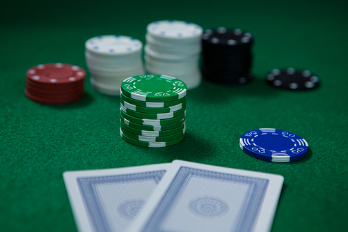 Close-up of chips with cards on green table