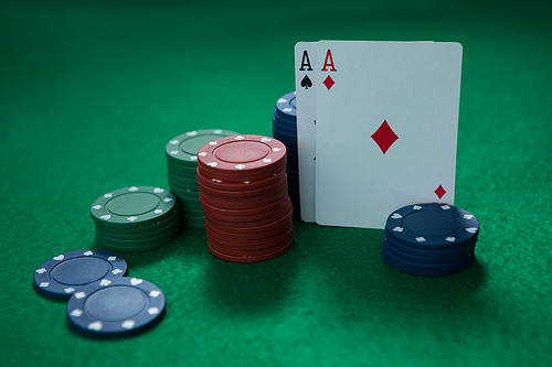 Close-up of aces and chips on green table