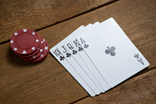 High angle view of cards and maroon chips on wooden table