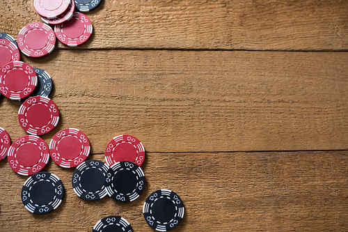 Overhead view of maroon and black chips on wooden table