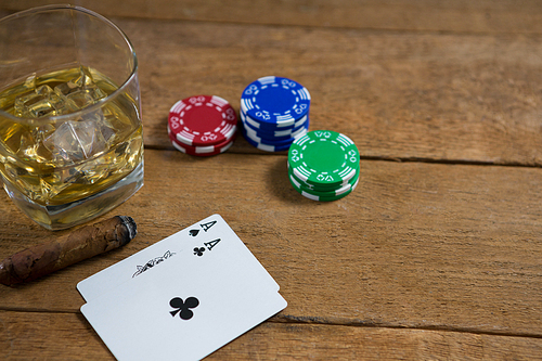 High angle view of whisky by cards and chips on wooden table