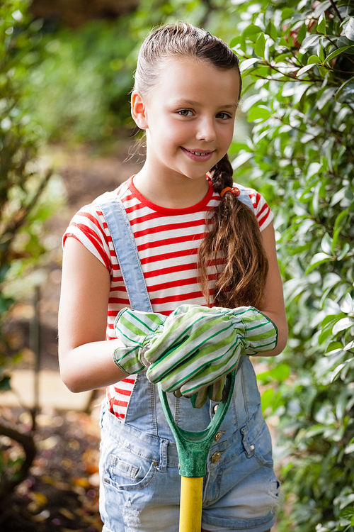 Portrait of smiling girl standing with gardening fork at backyard