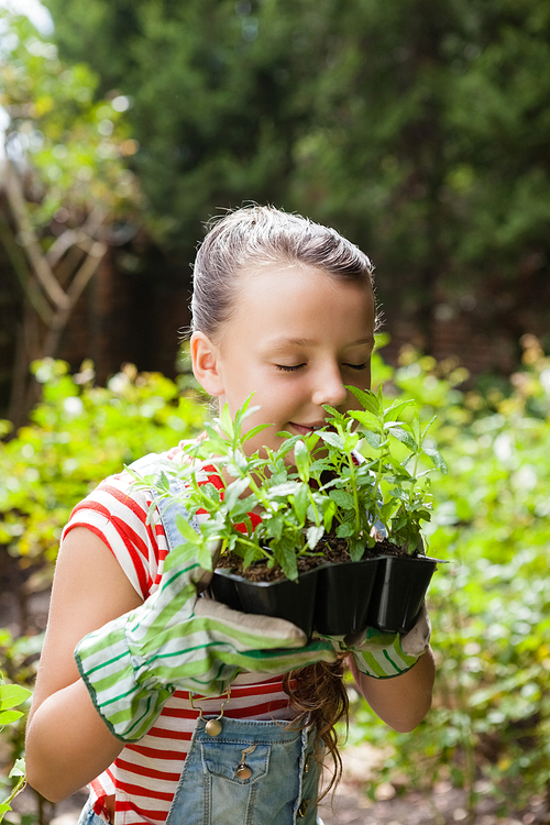 Girl smelling plants with eyes closed at backyard