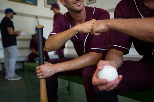 Cropped image of baseball players sitting on bench in locker room