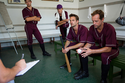 Serious basbeall team planning while sitting on bench at locker room