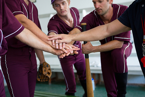 Close up of baseball team doing high five while standing at locker room