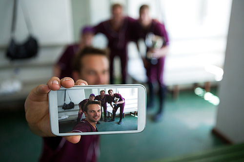 Close up of baseball team clicking selfie while standing at locker room after match