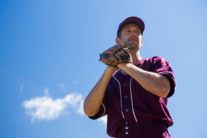 Low angle view of baseball pitcher standing against blue sky on sunny day