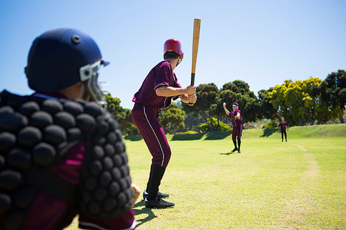 Players playing baseball together on field against clear blue sky