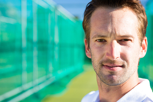 Close up portrait of young cricketer against net on field