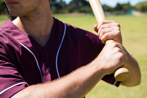 Mid section of player holding baseball bat at playing field