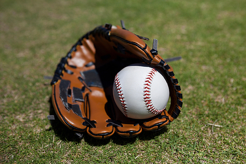 Close-up of baseball and glove on grassy field