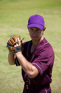 Portrait of confident baseball player wearing gloves standing at field