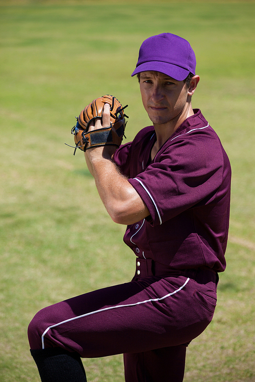 Confident baseball player playing on field during sunny day