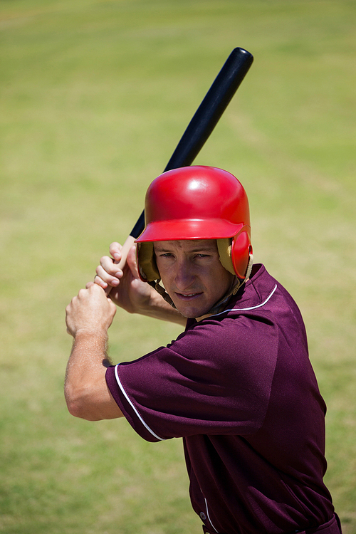 Confident baseball player with bat hitting at field during match