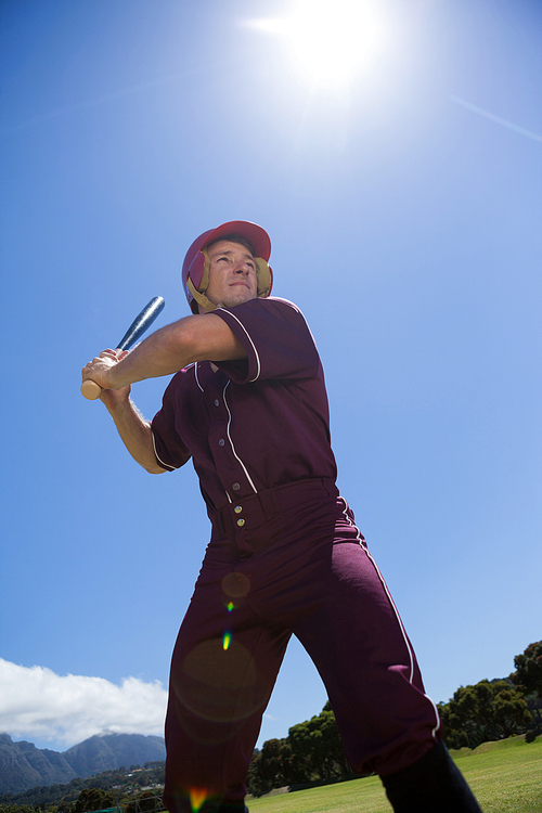 Low angle view of baseball player playing with bat against sky during sunny day