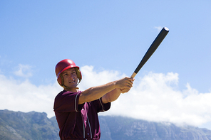 Baseball playing hitting with bat while standing against mountain and sky