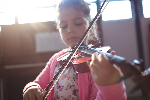 Girl student rehearsing violin in music class