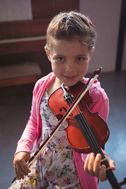 Portrait of girl student rehearsing violin in music class