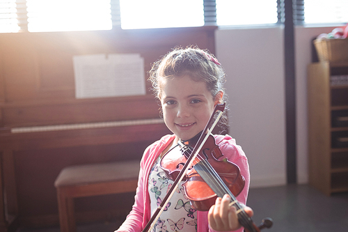 Portrait of smiling girl student rehearsing violin in music class