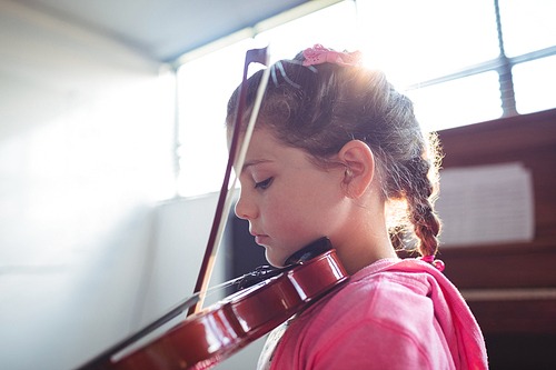 Side view of girl student rehearsing violin in music class