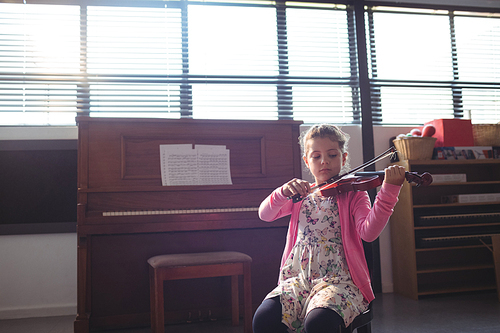 Schoolgirl rehearsing violin in music class