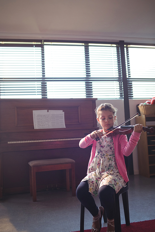 Elementary girl rehearsing violin in music class