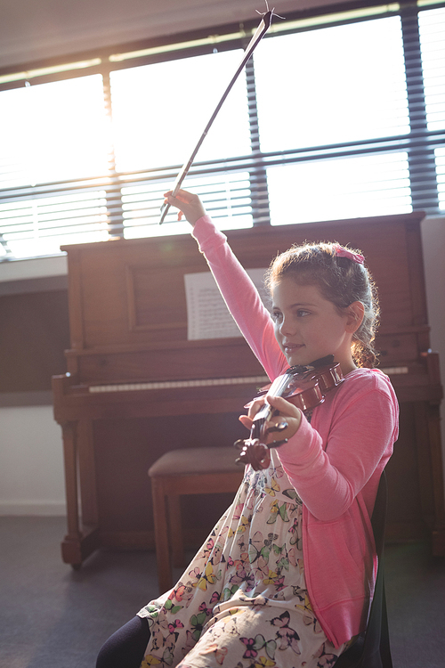 Cute girl rehearsing violin while sitting in music class