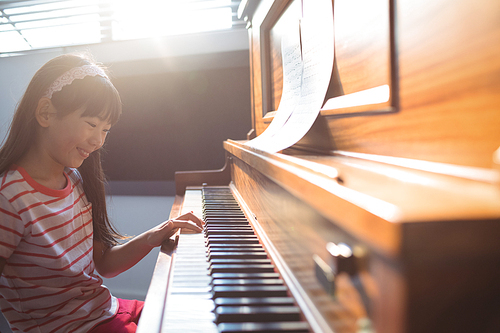 Smiling girl practicing piano in class at music school