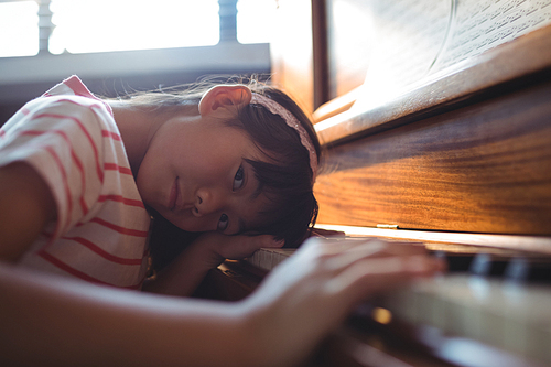 Portrait of girl leaning on piano in classroom at music school