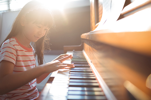 Smiling girl practicing piano in classroom at music school