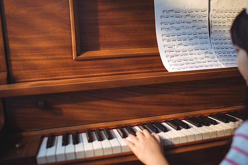 Cropped image of girl practicing piano in classroom at music school