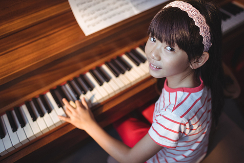 High angle portrait of girl practicing piano in classroom at music school