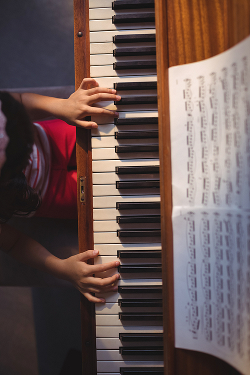 Overhead view of girl playing piano in classroom at music school