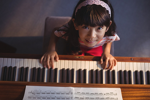 Overhead portrait of girl playing piano in classroom at music school