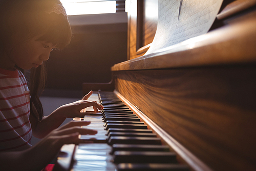 Focused girl practicing piano in classroom at music school