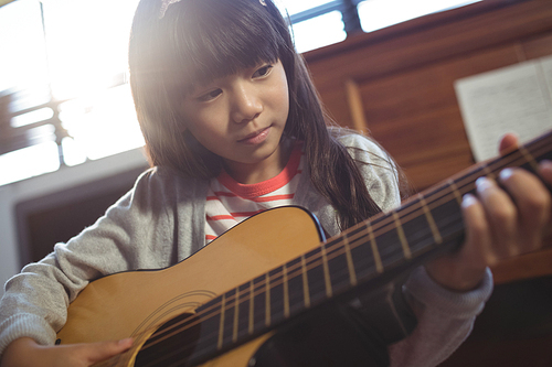 Concentrated girl practicing guitar at music class