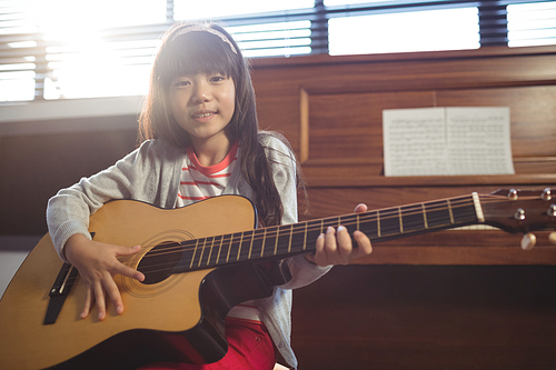 Portrait of girl practicing guitar at music class