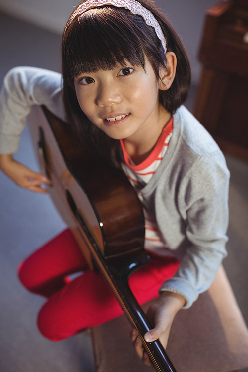 High angle portrait of girl practicing guitar at music class