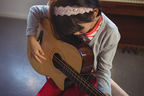 High angle view of girl practicing guitar at music class