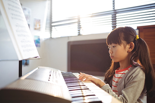 Concentrated girl practicing piano in class at school