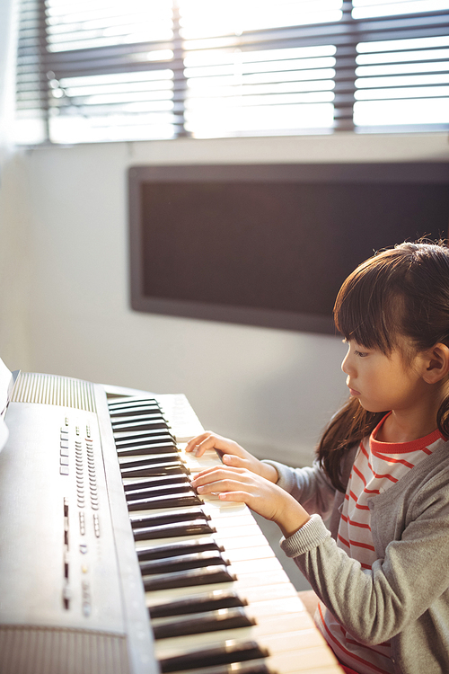 High angle view of concentrated girl practicing piano in class at school