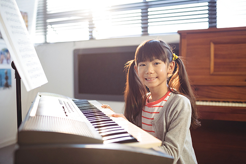 Portrait of smiling girl practicing piano in class at school