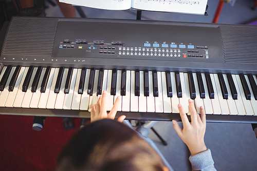 Cropped image of girl playing piano in class at school