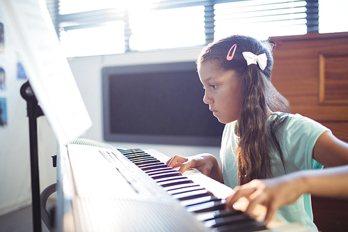 Concentrated elementary girl practicing piano in class at school