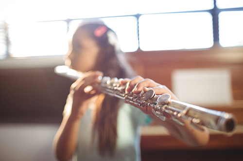 Girl practicing flute in classroom at music school