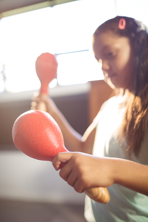 Girl playing maracas in classroom at music school