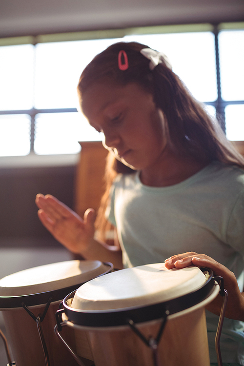 Girl practicing bongo drums in classroom at music school